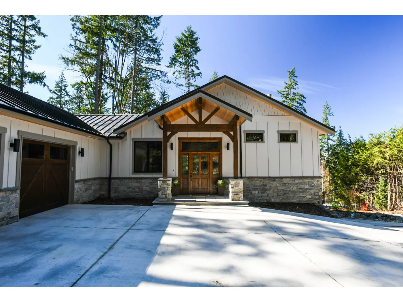 Lodge-style home in Issaquah: stone base, timber entry gable, metal roof, evening light